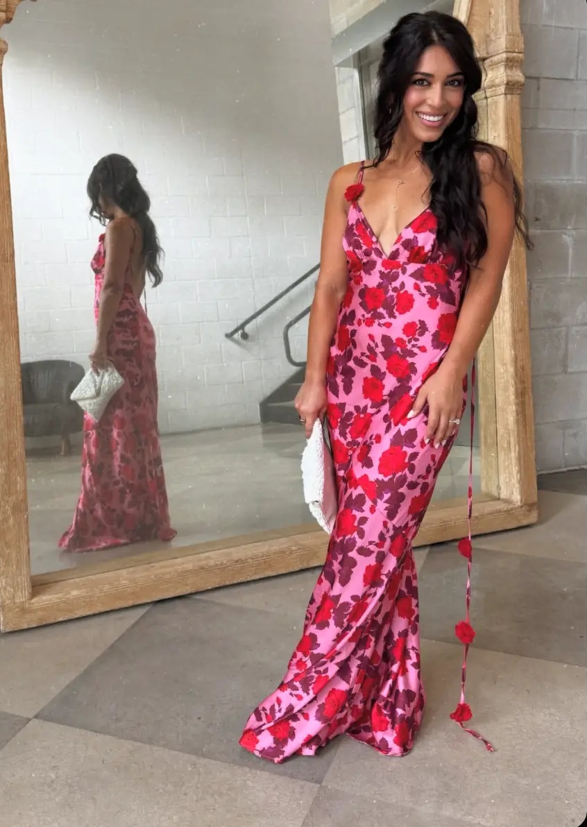 Rebecca Vargas in a floral dress beside a large mirror
